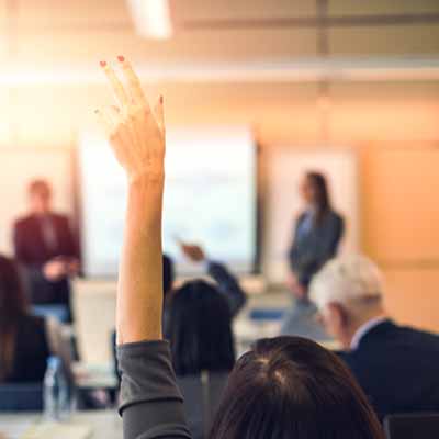 people in a metting with one person hand raised