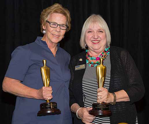 two women holding golden trophy awards